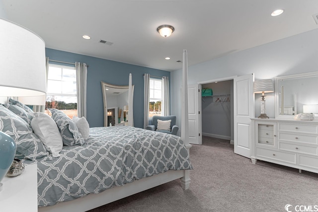 carpeted bedroom with multiple windows, visible vents, a walk in closet, and recessed lighting