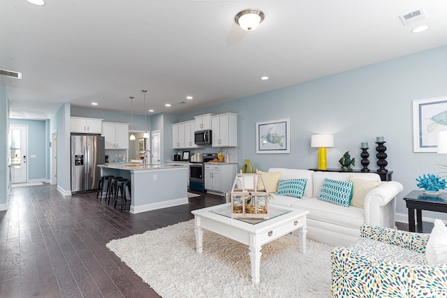 living room with recessed lighting, visible vents, dark wood finished floors, and baseboards