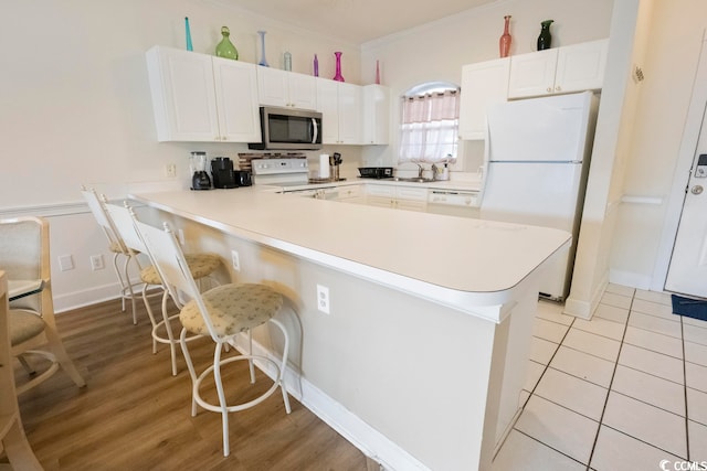 4856 Carnation Cir Unit 304, Myrtle Beach, SC 29577 - kitchen with light hardwood / wood-style floors, white appliances, white cabinetry, and a breakfast bar