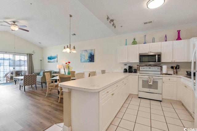 kitchen featuring white cabinets, electric range, pendant lighting, ceiling fan with notable chandelier, and vaulted ceiling