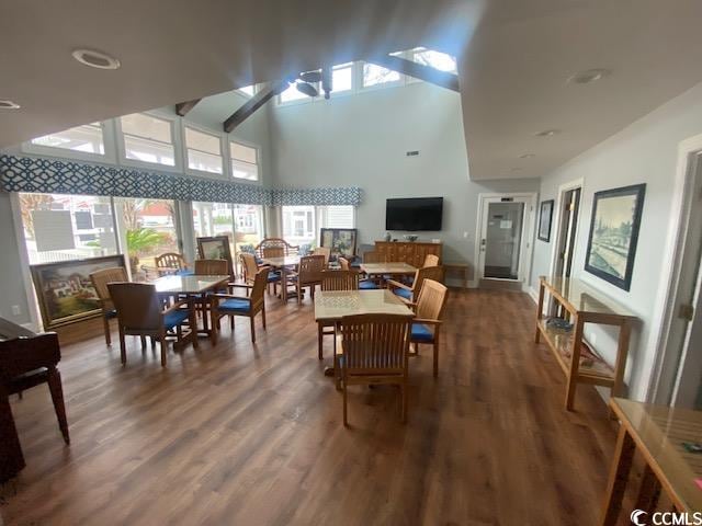 dining space featuring dark hardwood / wood-style floors, ceiling fan, and a towering ceiling