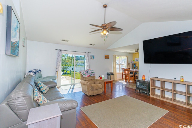 living room with ceiling fan, a wood stove, dark wood-type flooring, and vaulted ceiling