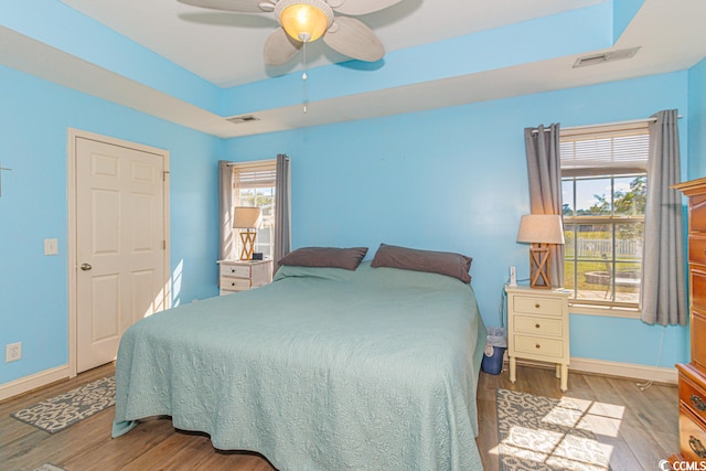 bedroom with multiple windows, light hardwood / wood-style flooring, and ceiling fan