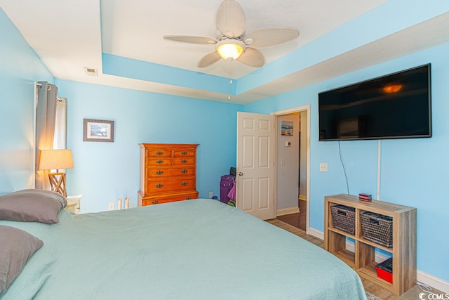 bedroom featuring dark wood-type flooring, ceiling fan, and a tray ceiling