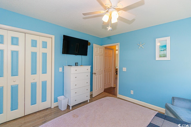 bedroom featuring a closet, light hardwood / wood-style floors, ceiling fan, and a textured ceiling