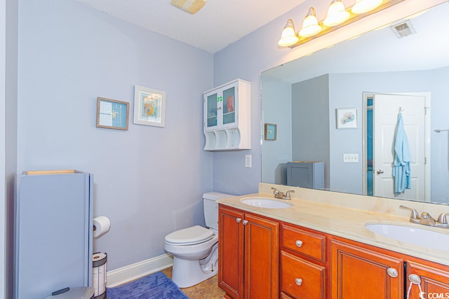 bathroom featuring tile flooring, oversized vanity, dual sinks, and toilet