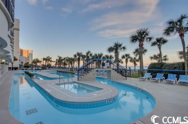 pool at dusk featuring a community hot tub and a patio