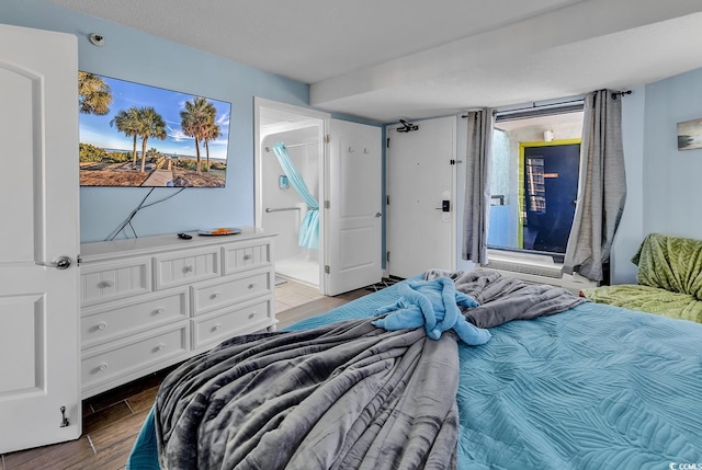 bedroom featuring wood tiled floor, multiple windows, and connected bathroom