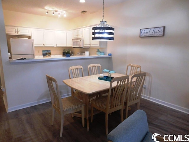 dining area featuring a chandelier, rail lighting, and dark hardwood / wood-style floors