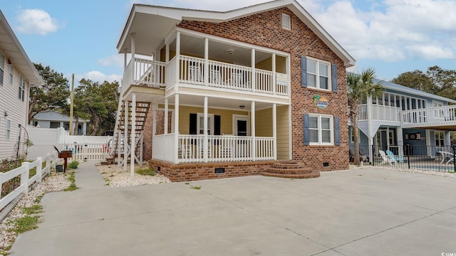 back of property featuring covered porch, fence, and brick siding