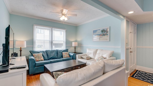 living room featuring ornamental molding, ceiling fan, a textured ceiling, and light wood finished floors