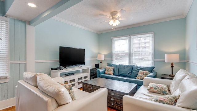 living area featuring a textured ceiling, ornamental molding, and a ceiling fan