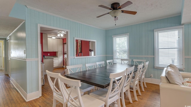 dining area featuring ornamental molding, light wood-style floors, and a textured ceiling