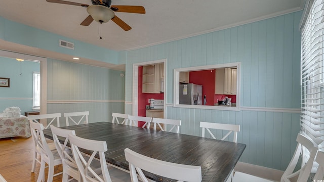 dining space with ceiling fan, visible vents, wood finished floors, and ornamental molding