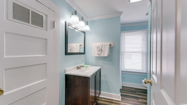 bathroom featuring visible vents, baseboards, wood finished floors, crown molding, and vanity