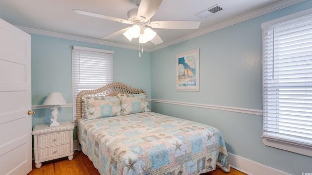 bedroom featuring multiple windows, wood finished floors, visible vents, and crown molding