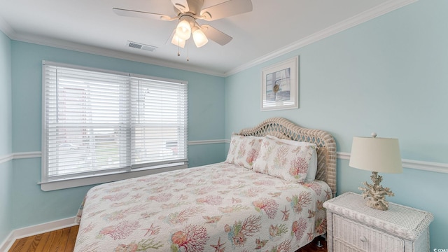 bedroom featuring baseboards, multiple windows, ornamental molding, and wood finished floors