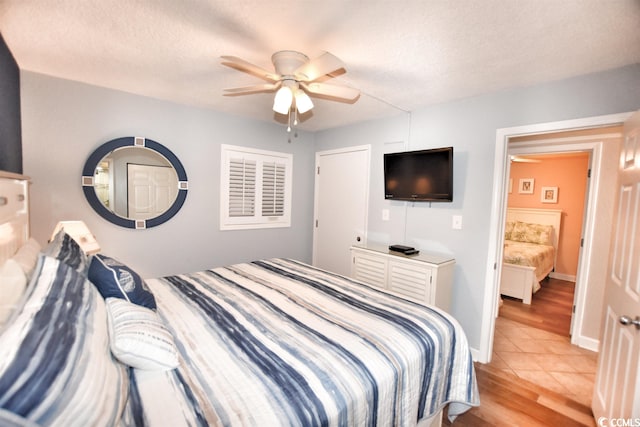 bedroom with light hardwood / wood-style floors, a textured ceiling, and ceiling fan