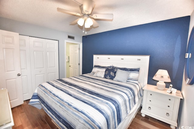 bedroom featuring dark wood-type flooring, a textured ceiling, a closet, and ceiling fan