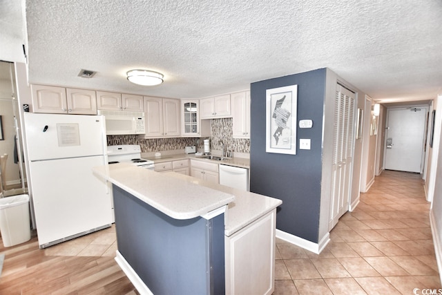 kitchen with tasteful backsplash, white appliances, sink, a textured ceiling, and light tile patterned floors