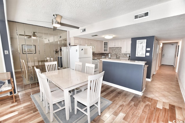 dining room with light hardwood / wood-style floors, a textured ceiling, and ceiling fan