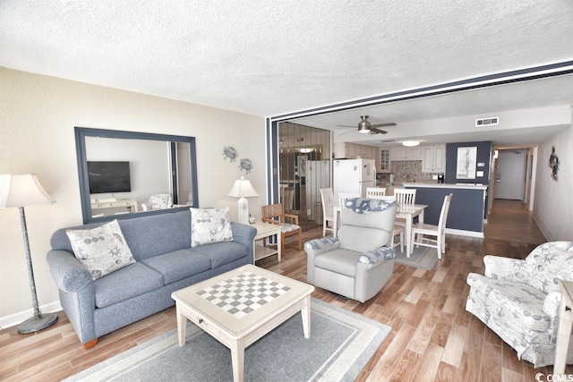 living room with a textured ceiling, hardwood / wood-style flooring, and ceiling fan