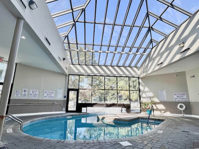 view of swimming pool with glass enclosure, a patio area, and a jacuzzi