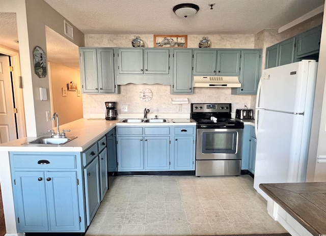 kitchen with a textured ceiling, sink, stainless steel electric range oven, and white refrigerator