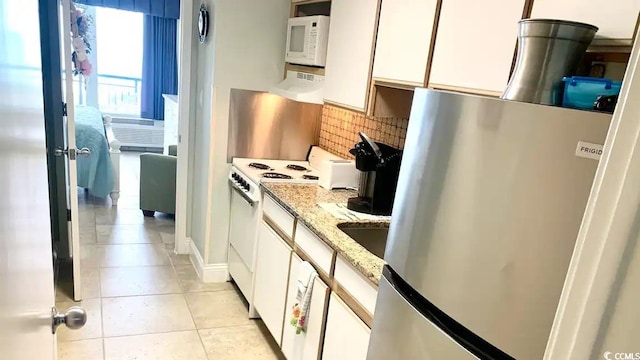 kitchen featuring white appliances, white cabinets, light stone countertops, tasteful backsplash, and light tile patterned flooring