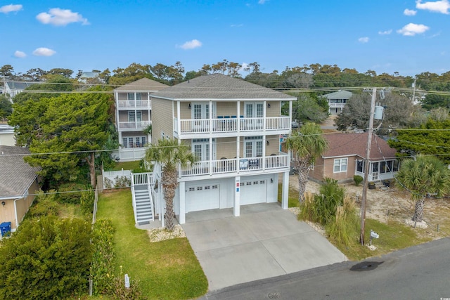 beach home with a balcony, a front lawn, and a garage