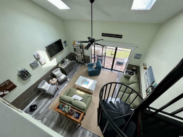 living room with a towering ceiling, hardwood / wood-style flooring, and ceiling fan