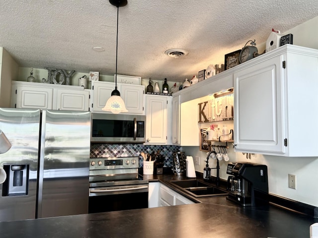 kitchen featuring a textured ceiling, stainless steel appliances, sink, decorative light fixtures, and white cabinetry