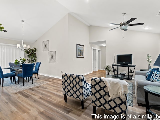 living room with wood-type flooring, ceiling fan with notable chandelier, and high vaulted ceiling