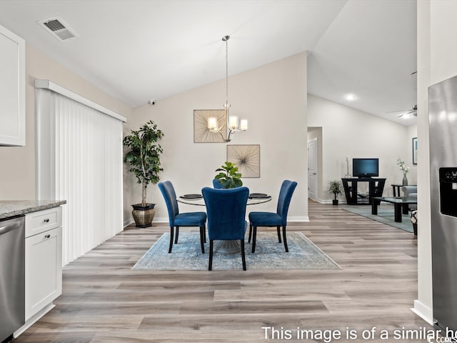 dining area with ceiling fan with notable chandelier, lofted ceiling, and light hardwood / wood-style floors