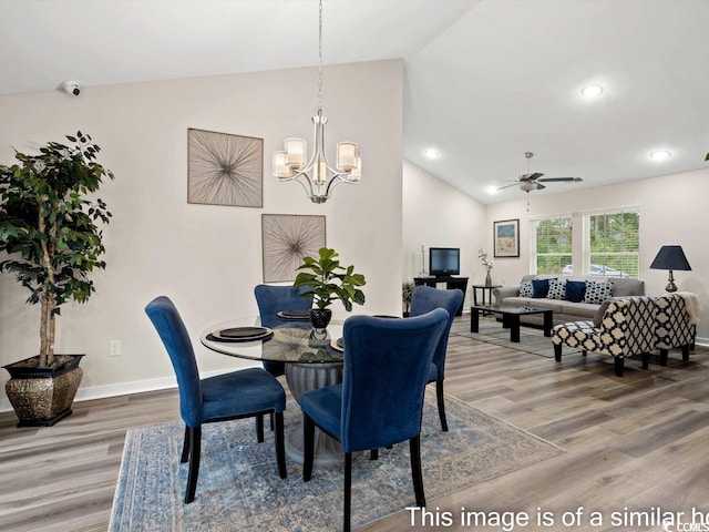 dining area featuring ceiling fan with notable chandelier, lofted ceiling, and hardwood / wood-style floors