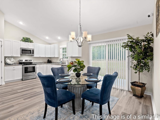 dining space with light wood-type flooring, vaulted ceiling, an inviting chandelier, and sink