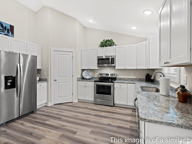 kitchen featuring appliances with stainless steel finishes, light hardwood / wood-style floors, white cabinetry, light stone countertops, and sink