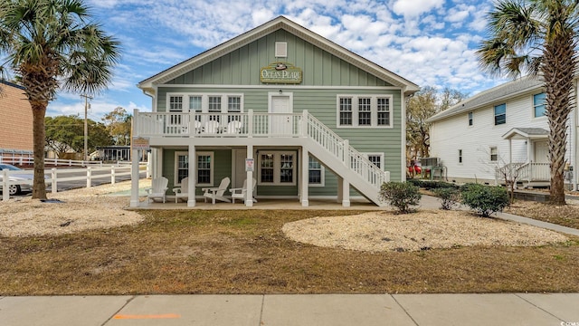 rear view of house with a patio area, stairs, fence, and board and batten siding