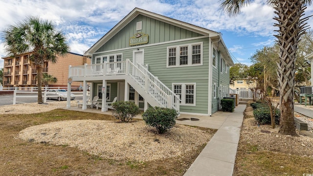 rear view of house featuring stairway, board and batten siding, a patio area, fence, and a deck