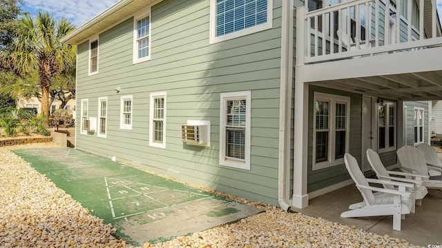 view of side of home featuring a patio area, a balcony, and shuffleboard