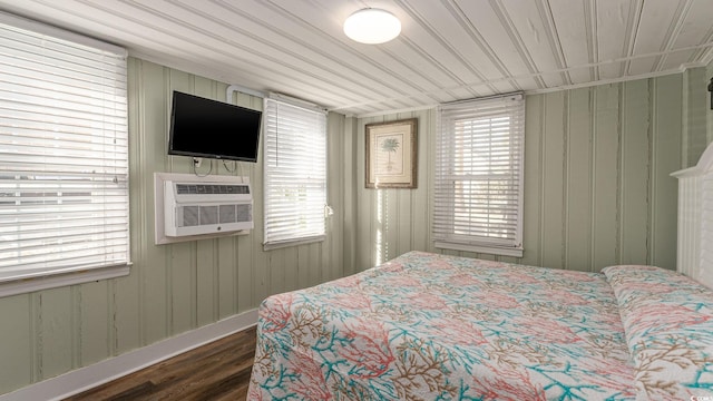 bedroom featuring multiple windows, a wall mounted AC, and wood finished floors