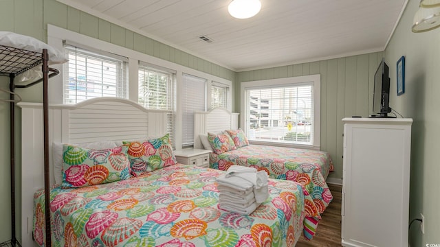 bedroom with wooden walls, wood finished floors, and crown molding