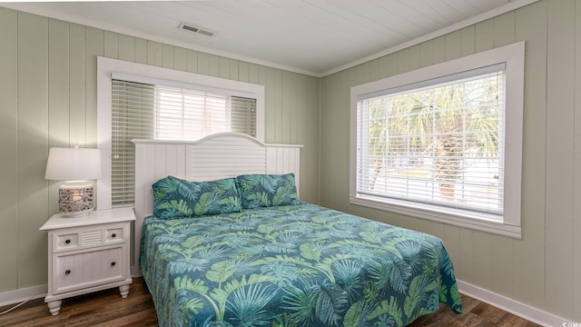 bedroom featuring dark wood-style flooring, visible vents, crown molding, and baseboards