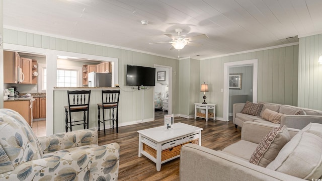 living area with ornamental molding, a ceiling fan, visible vents, and wood finished floors