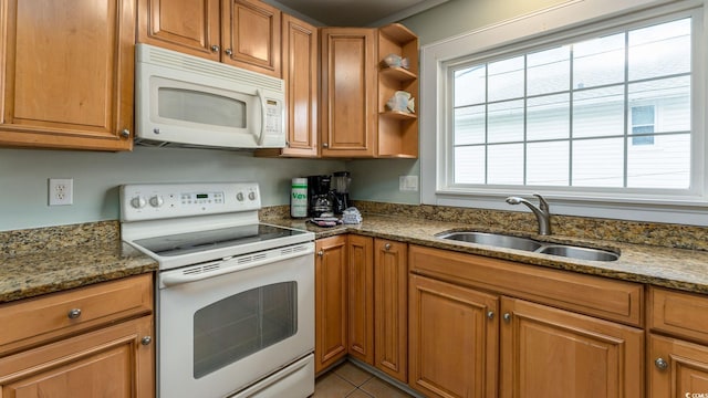 kitchen with white appliances, dark stone counters, brown cabinetry, open shelves, and a sink