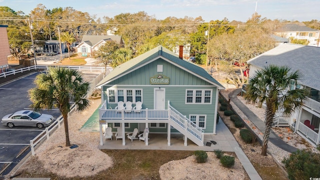 rear view of house with stairs, a patio, board and batten siding, and covered porch