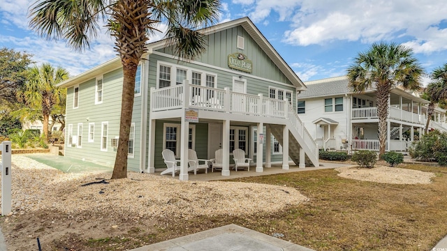 rear view of house with stairway, board and batten siding, and a patio area