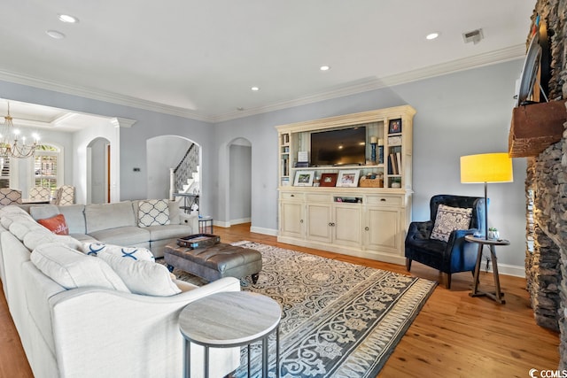 living room with light wood-type flooring, a notable chandelier, and ornamental molding