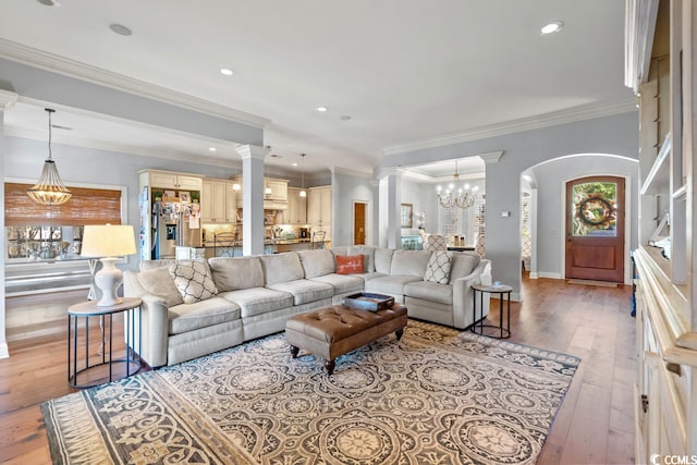 living room with plenty of natural light, an inviting chandelier, ornamental molding, and light hardwood / wood-style flooring