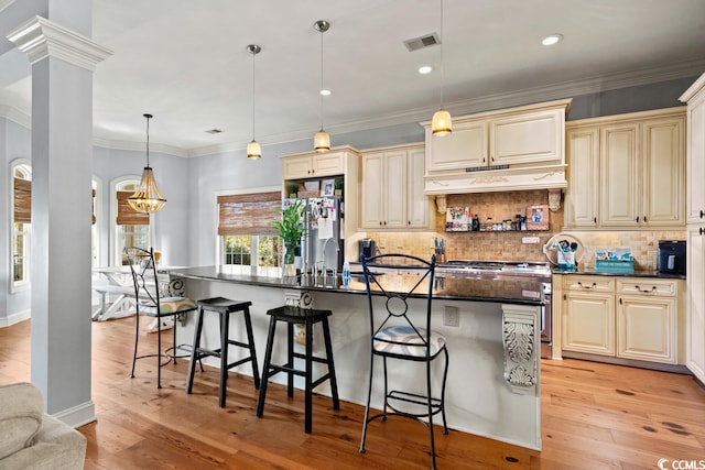 kitchen with a kitchen breakfast bar, pendant lighting, an island with sink, custom exhaust hood, and light wood-type flooring